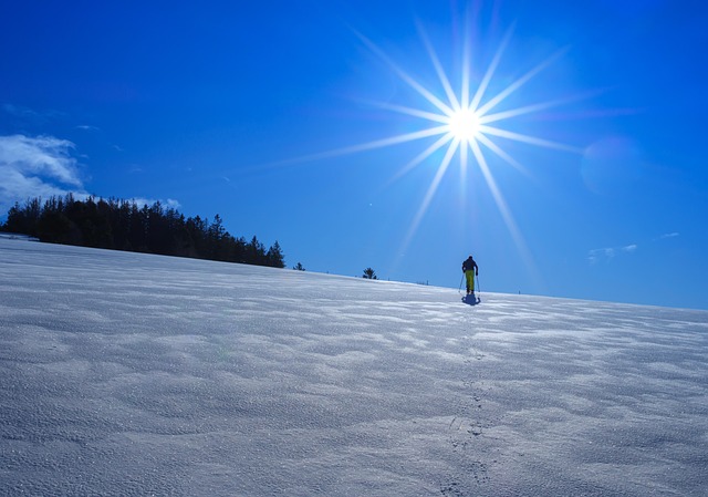Henkilö liukulumikenkäilee aurinkoisella rinteellä
